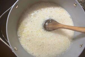 Medium-sized pot with oil, salt, water, and white rice. Step 4 of the Dominican Style Long-grain white rice recipe