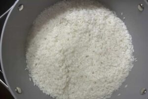 Medium-sized pot with oil, salt, water, and white rice. The picture shows the water level and how the rice looks before covering it. Step 5 of the Dominican Style Long-grain white rice recipe