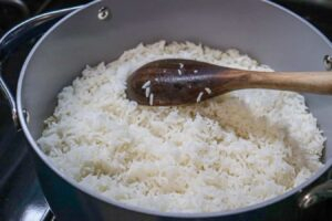 Medium-sized pot with oil, salt, water, and white rice. The picture shows the fluffiness of the white rice once it is done. Step 6 of the Dominican Style Long-grain white rice recipe