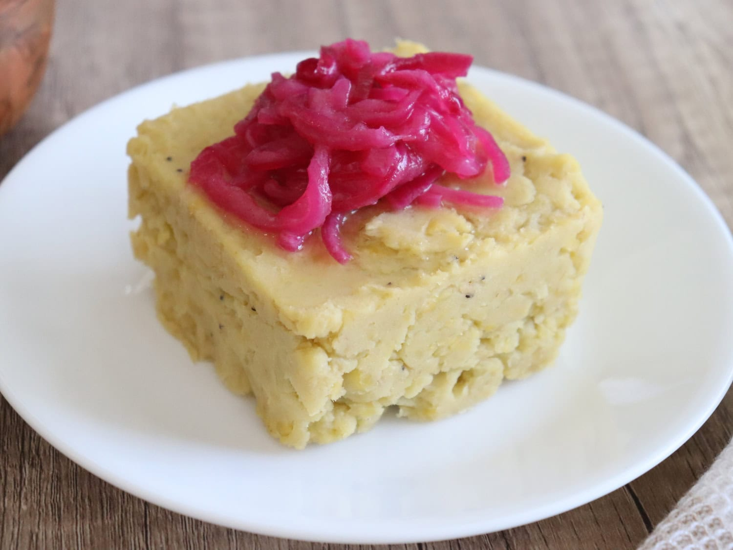 serving of Dominican mangú topped with pickled red onions on a white plate.