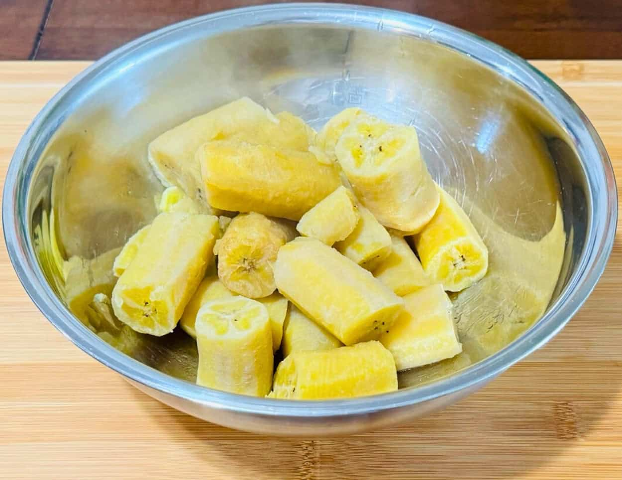 Boiled green plantains resting in a stainless steel bowl, ready to be mashed.