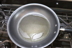 Dominican sautéed onions neutral oil heating in a skillet before adding onion