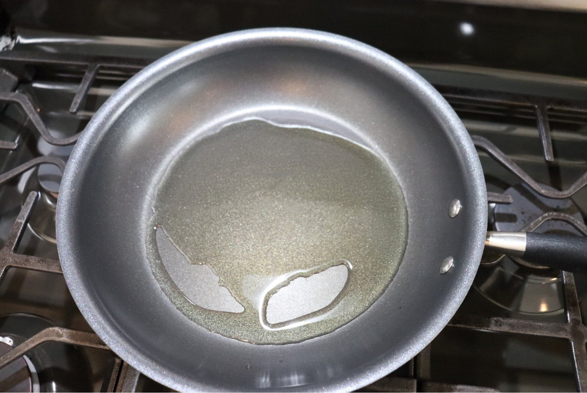 Dominican sautéed onions neutral oil heating in a skillet before adding onion