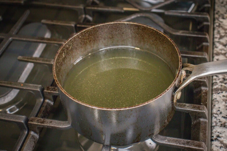 Small pot of oil heating on a stovetop, preparing oil for frying plantains.