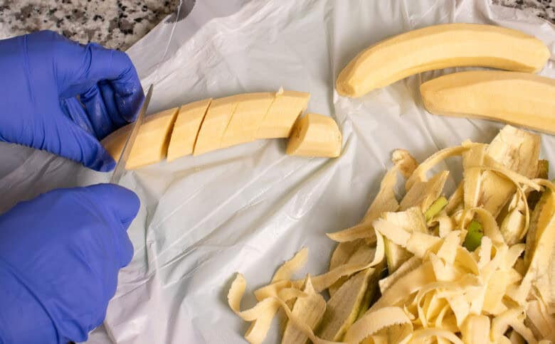 Peeled plantains being cut into chunks for frying, with the peels set aside.