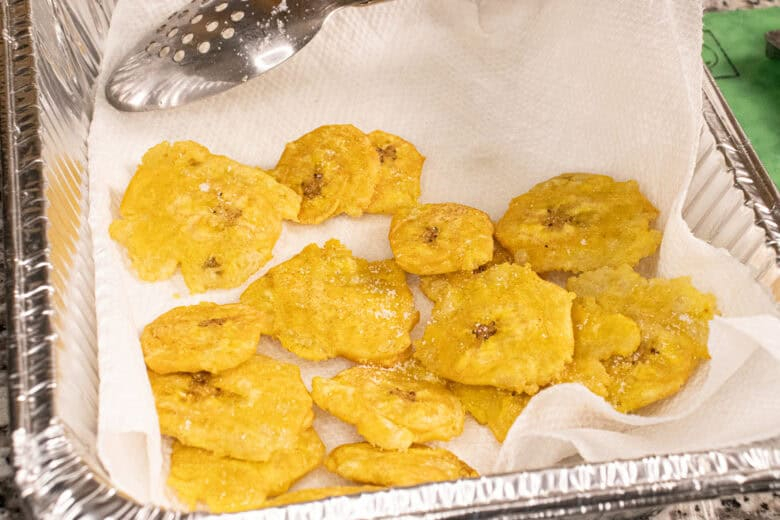 Crispy tostones draining on paper towels after the second fry