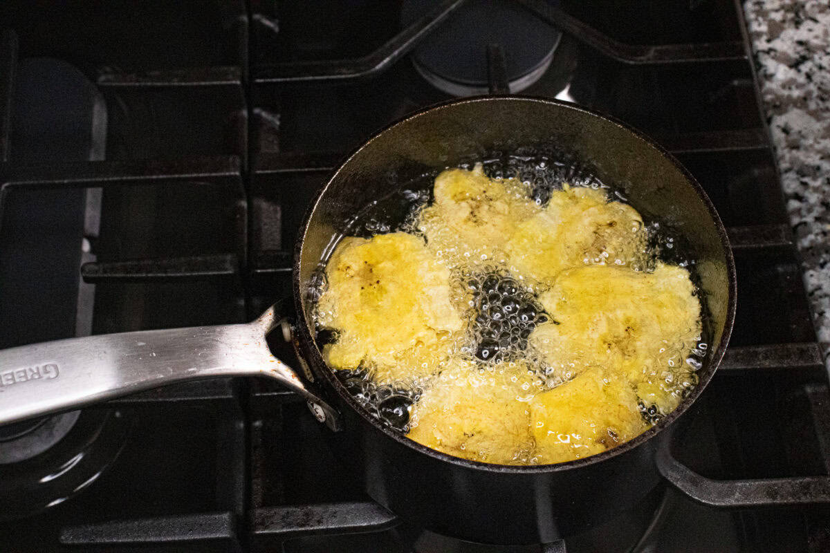 Smashed plantains frying in hot oil during the second fry for tostones