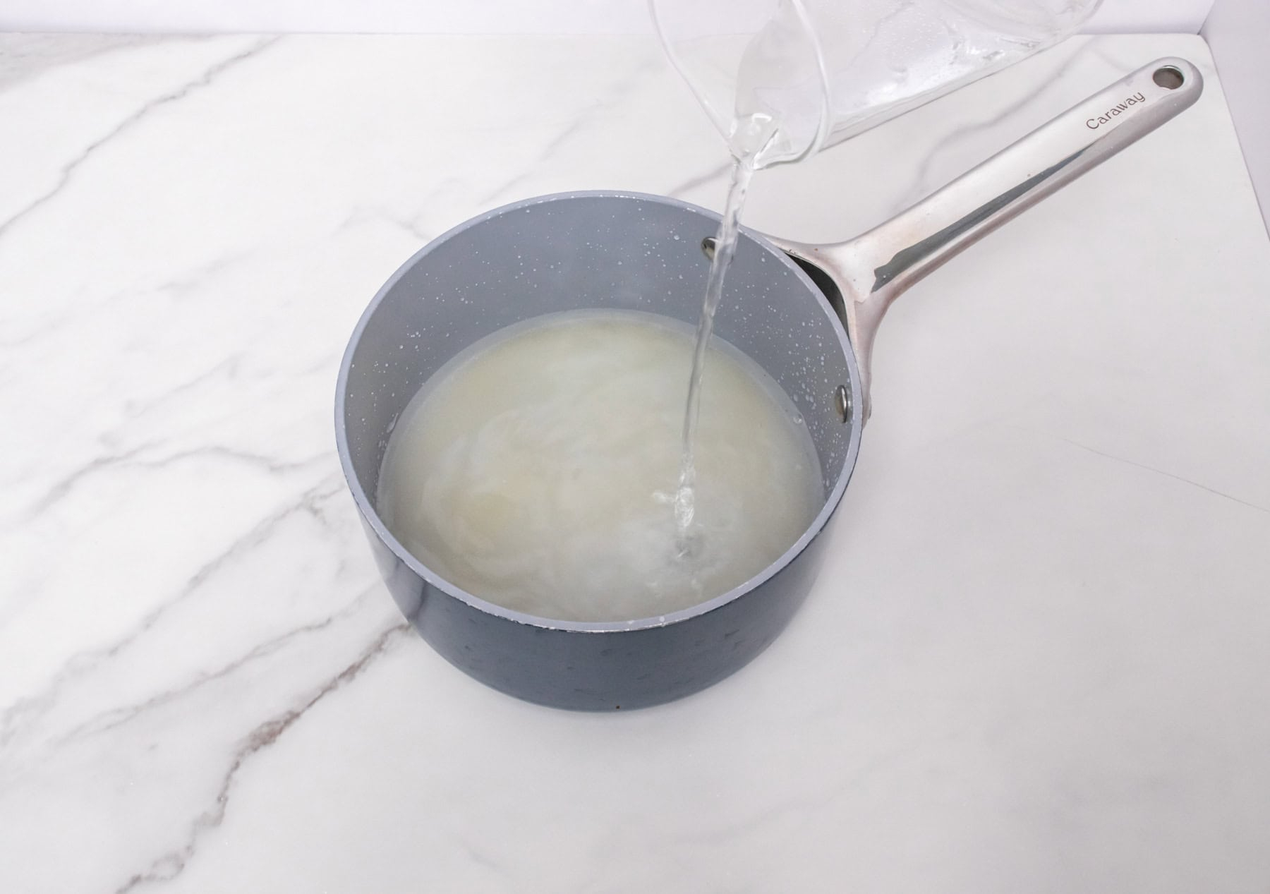 Water being poured into a saucepan to make homemade simple syrup