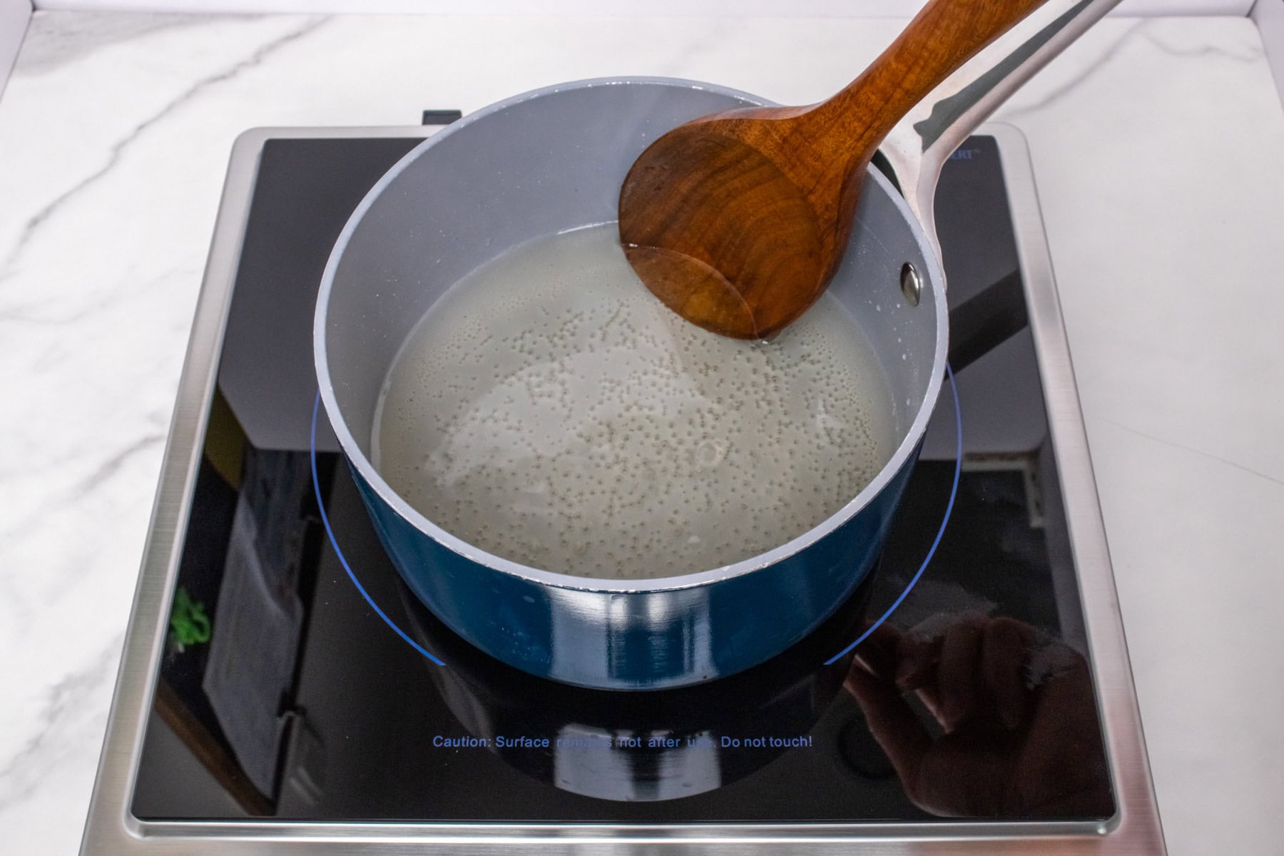 Simple syrup being stirred in a saucepan as the sugar dissolves