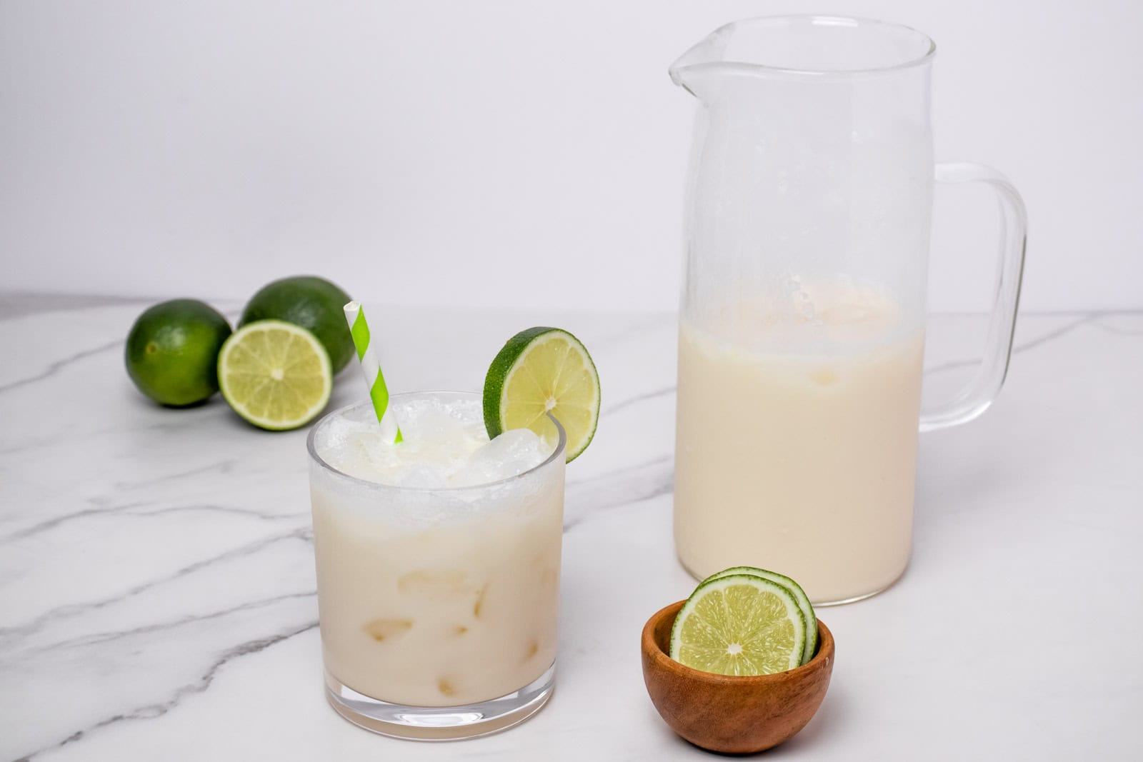 Finished Morir Soñando de Limón served over ice with fresh limes and a pitcher in the background.