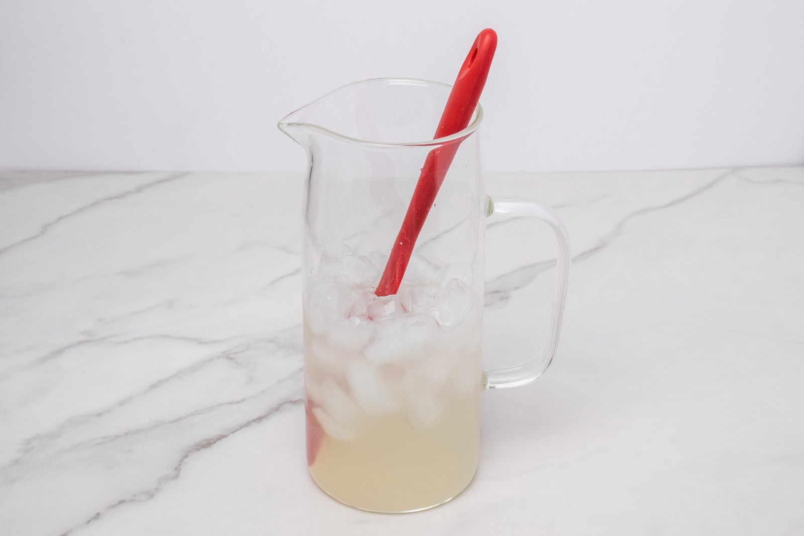 Ice added to the lime mixture in a glass pitcher for Morir Soñando de Limón.