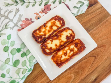 Golden Dominican fried cheese with browned edges served on a white plate